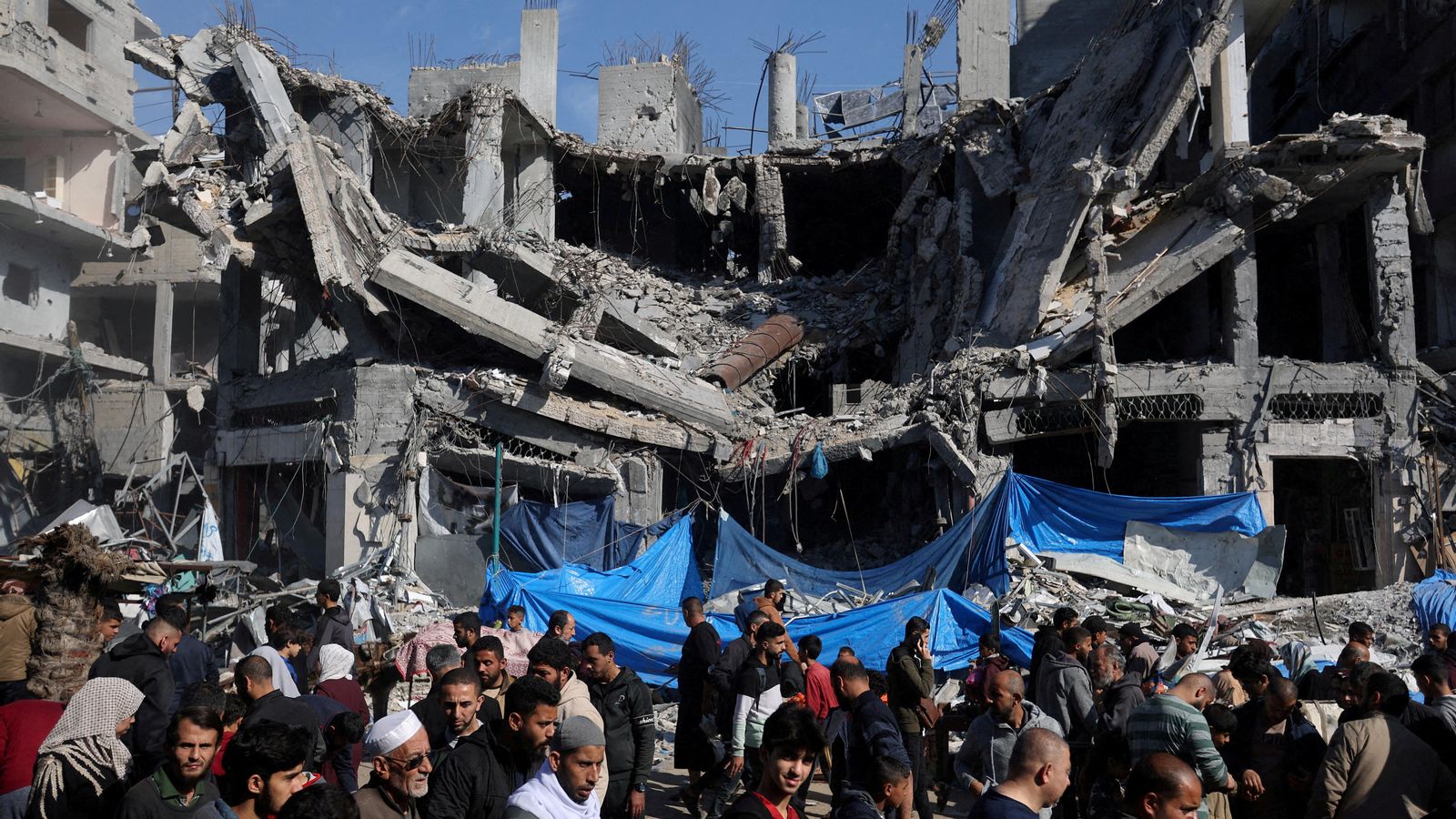 Un grup de palestins al costat d'un edifici residencial destruït en el camp de refugiats de Nuseirat