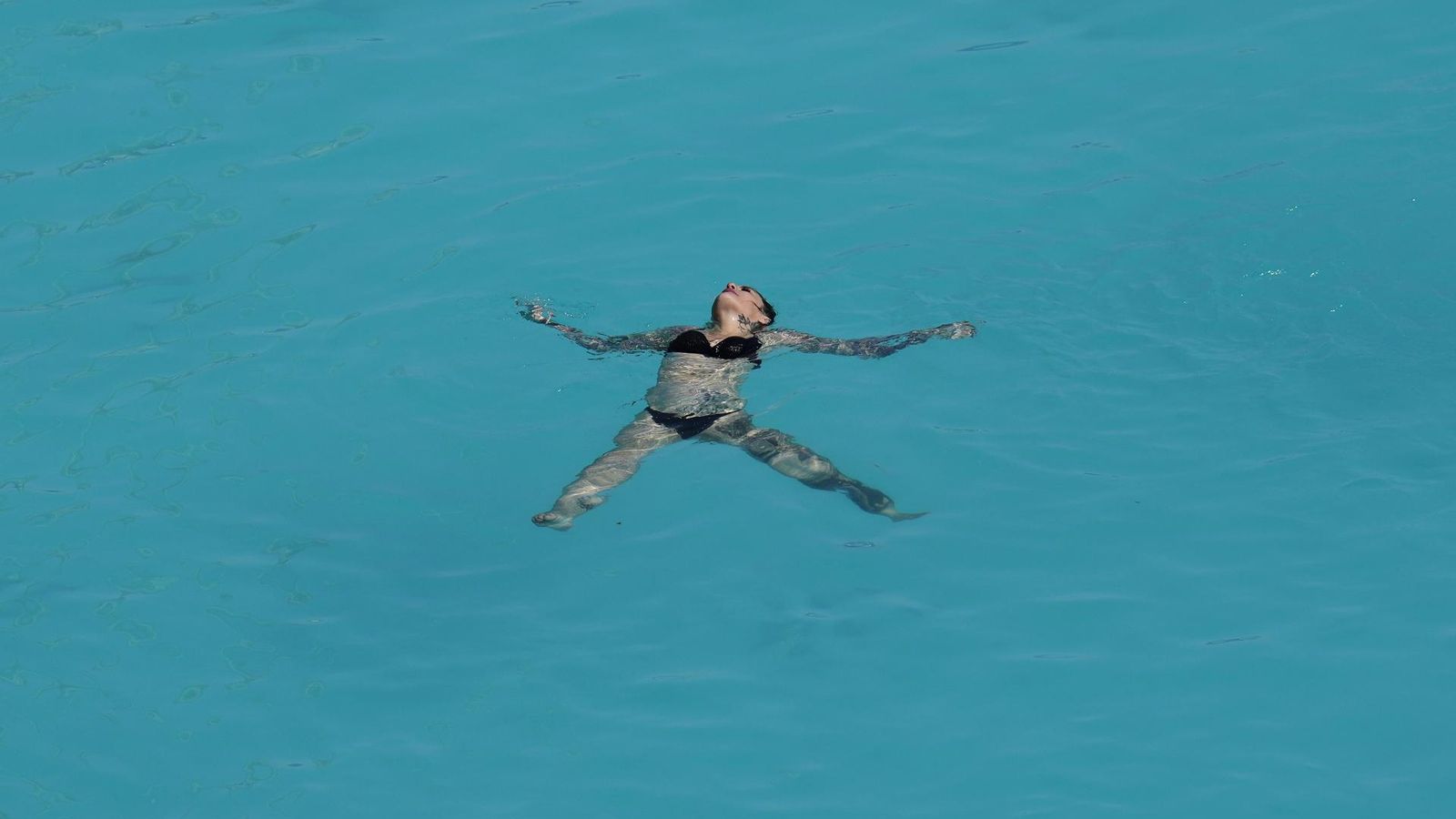 Una dona es refresca en una piscina