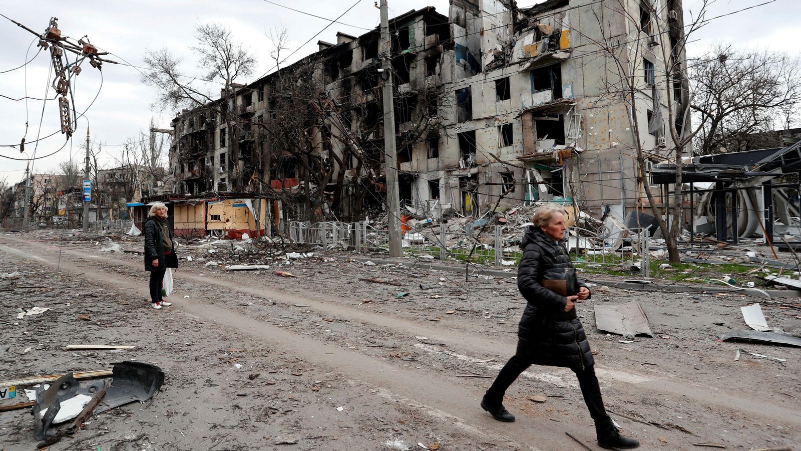 Dos dones passen per davant d'un edifici destruït a Mariúpol