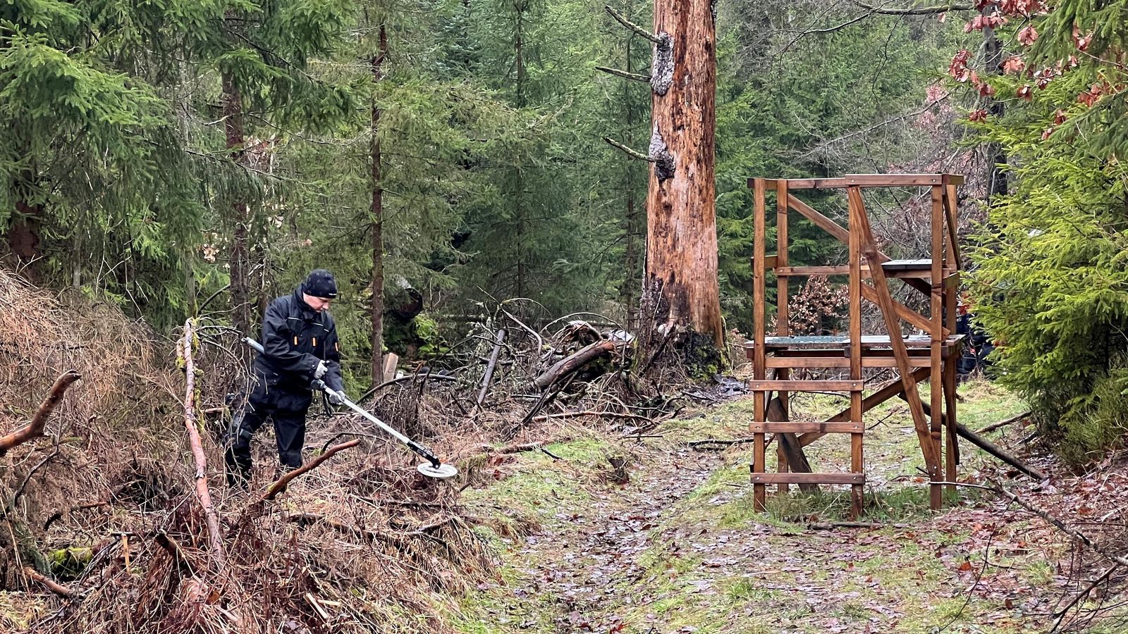 Un agent de policia alemany busca l'arma del crim amb un detector de metalls en el lloc en què va aparéixer el cadàver