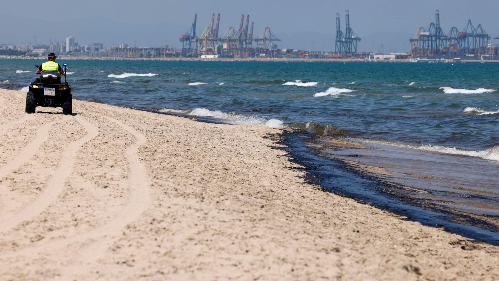 El vessament que ha arribat fins a les platges del sud de València, on s'aprecia les grues del port al fons