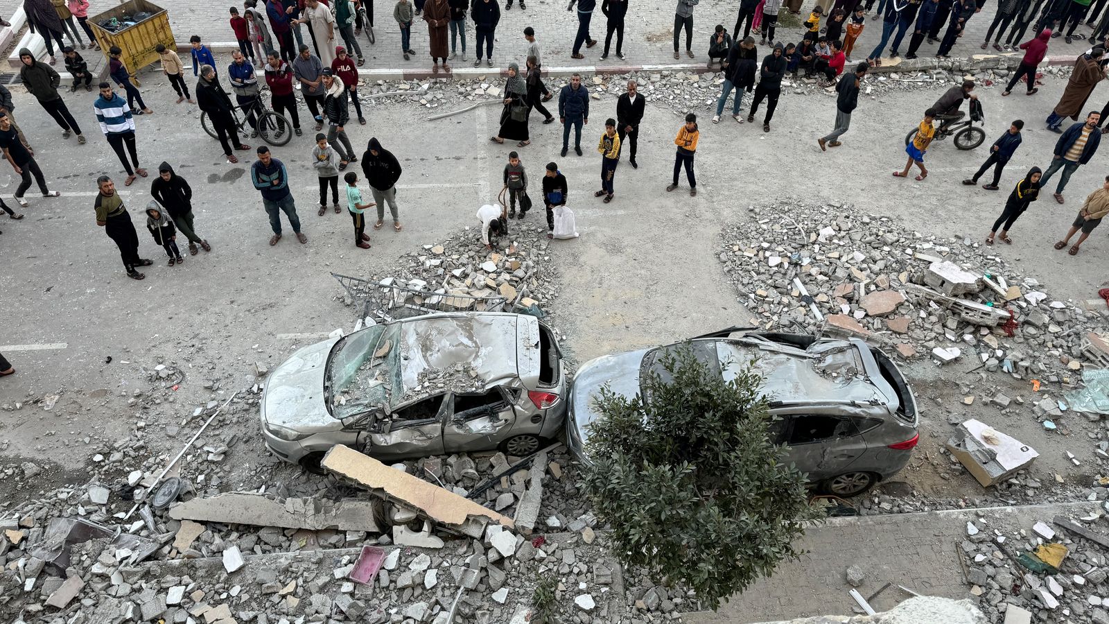 Un grup de palestins contemplen restes de vehicles danyats després d'un atac israelià a edifici residencial de Khan Younis, al sud de la Franja de Gaza