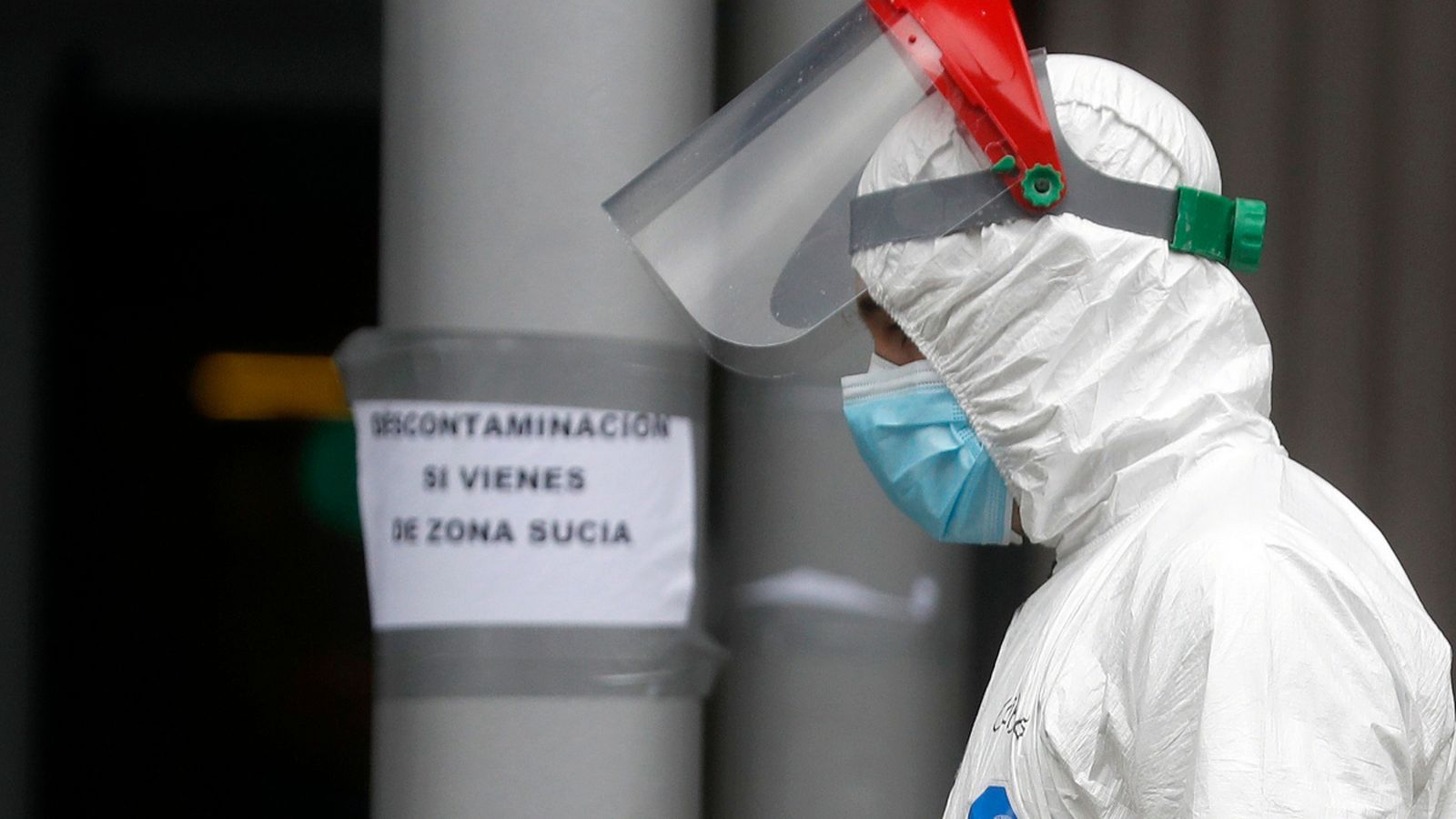 Un treballador, amb protecció, creua la zona comuna de l'hospital habilitat a Ifema, Madrid