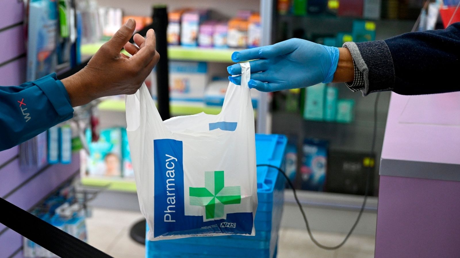 Un farmacèutic de Londres atén un client respectant la distància de seguretat