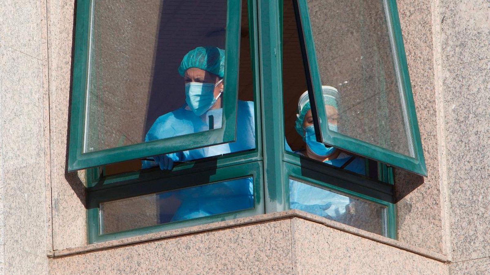 Dues treballadores d'una residència de Galícia, on s'ha detectat un brot nombrós, junt a la finestra del centre on treballen