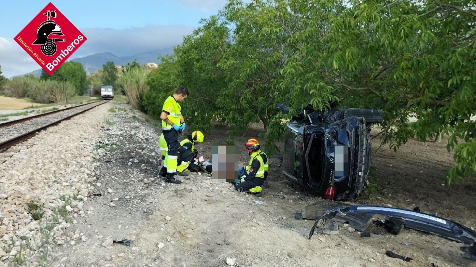 Efectius dels bombers ofereixen una primera atenció als dos ferits junt a les vies del tren a Agres