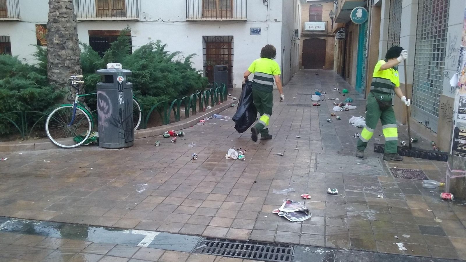 Treballadores municipals netejen les restes d'un botellot al barri de Benimaclet (València)