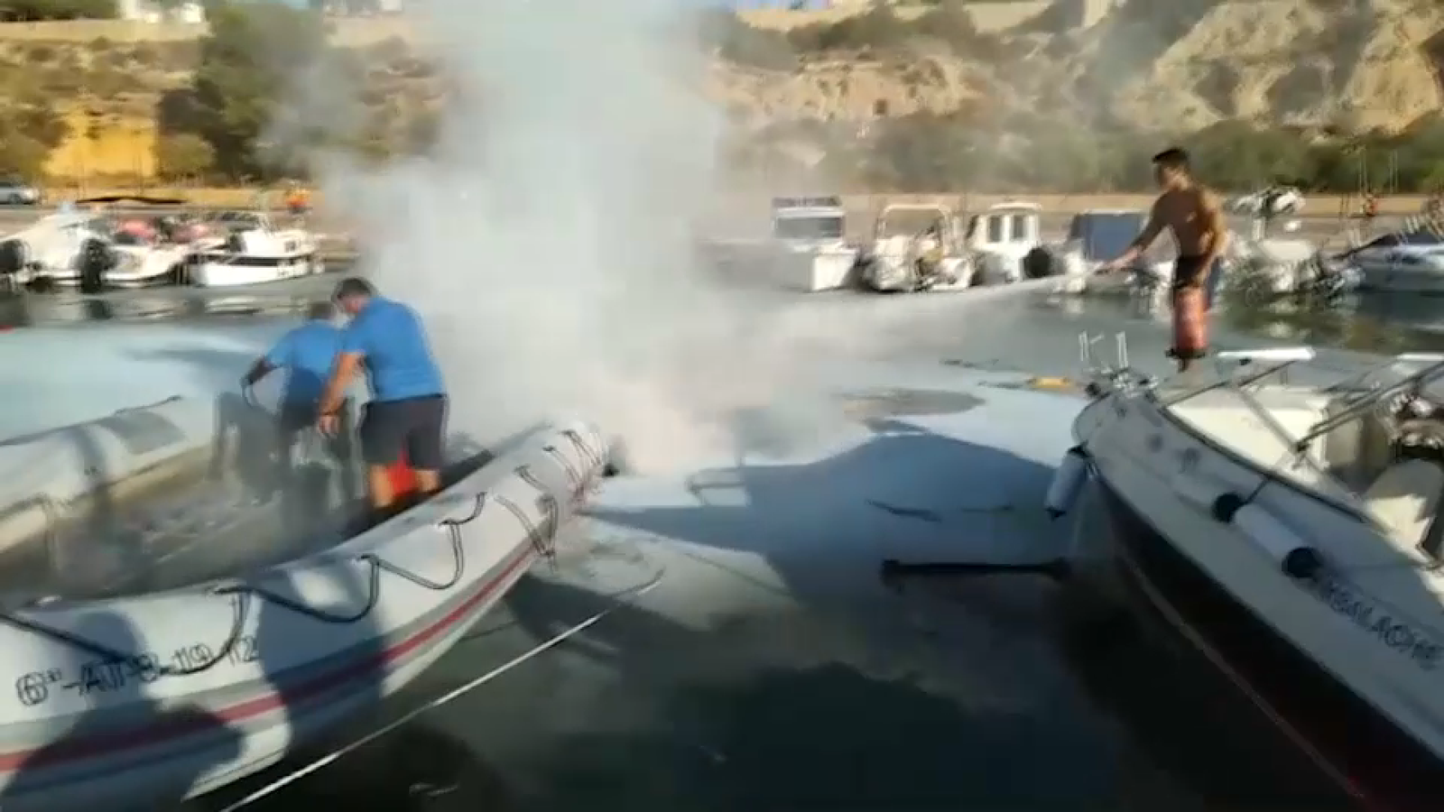 Els treballadors del ports apaguen el foc amb exintors i mànegues d'aigua