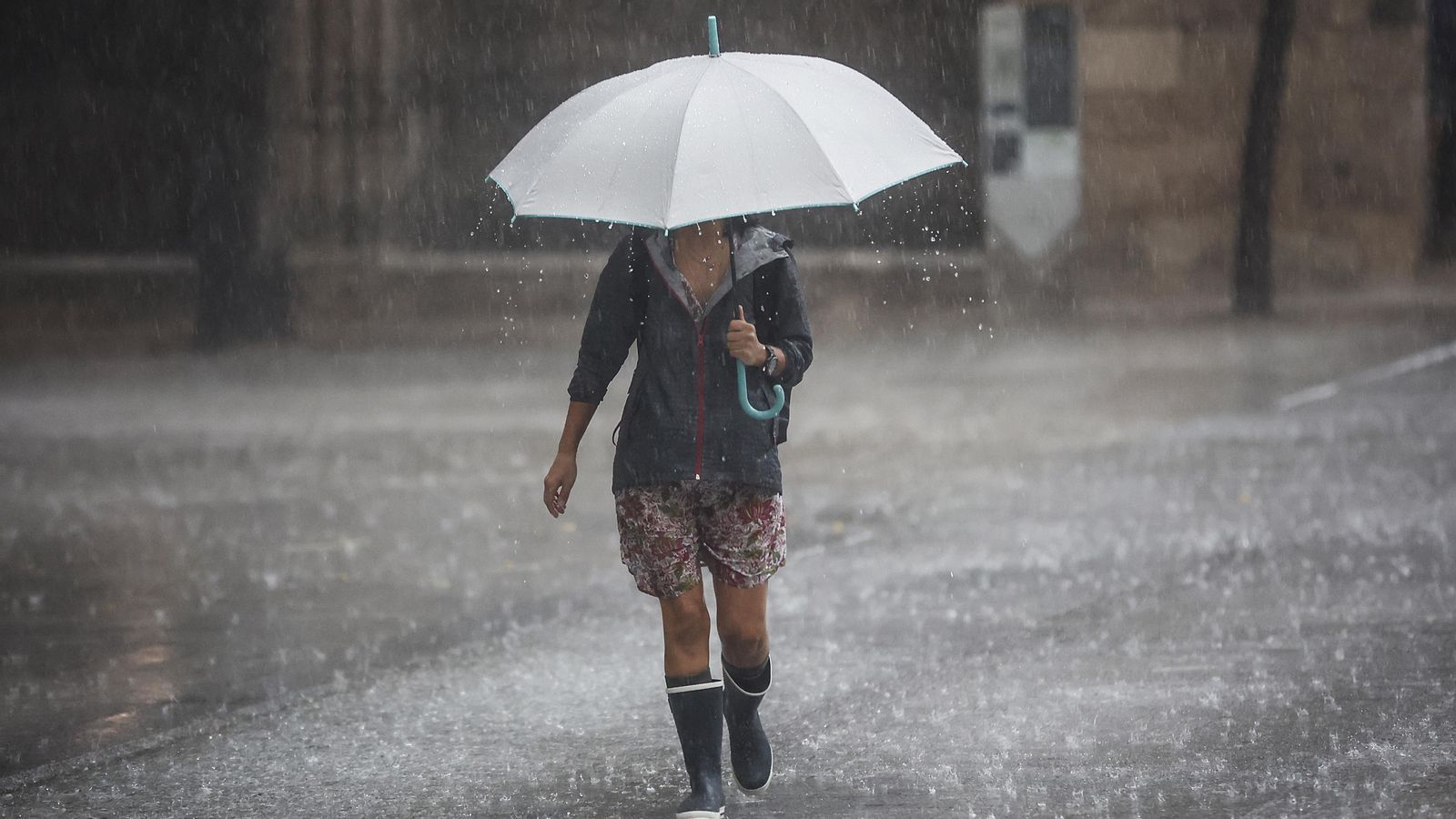 Una dona camina amb un paraigua sota la pluja, en una imatge d'arxiu Una dona camina amb un paraigua sota la pluja en una imatge d'arxiu