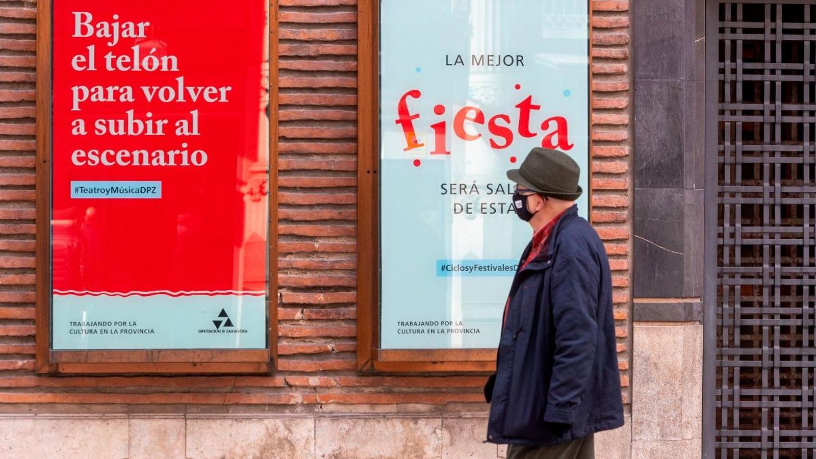 Un home passa davant un cartell de suport a la cultura a Saragossa, on els teatres hauran de tancar a les 20 hores