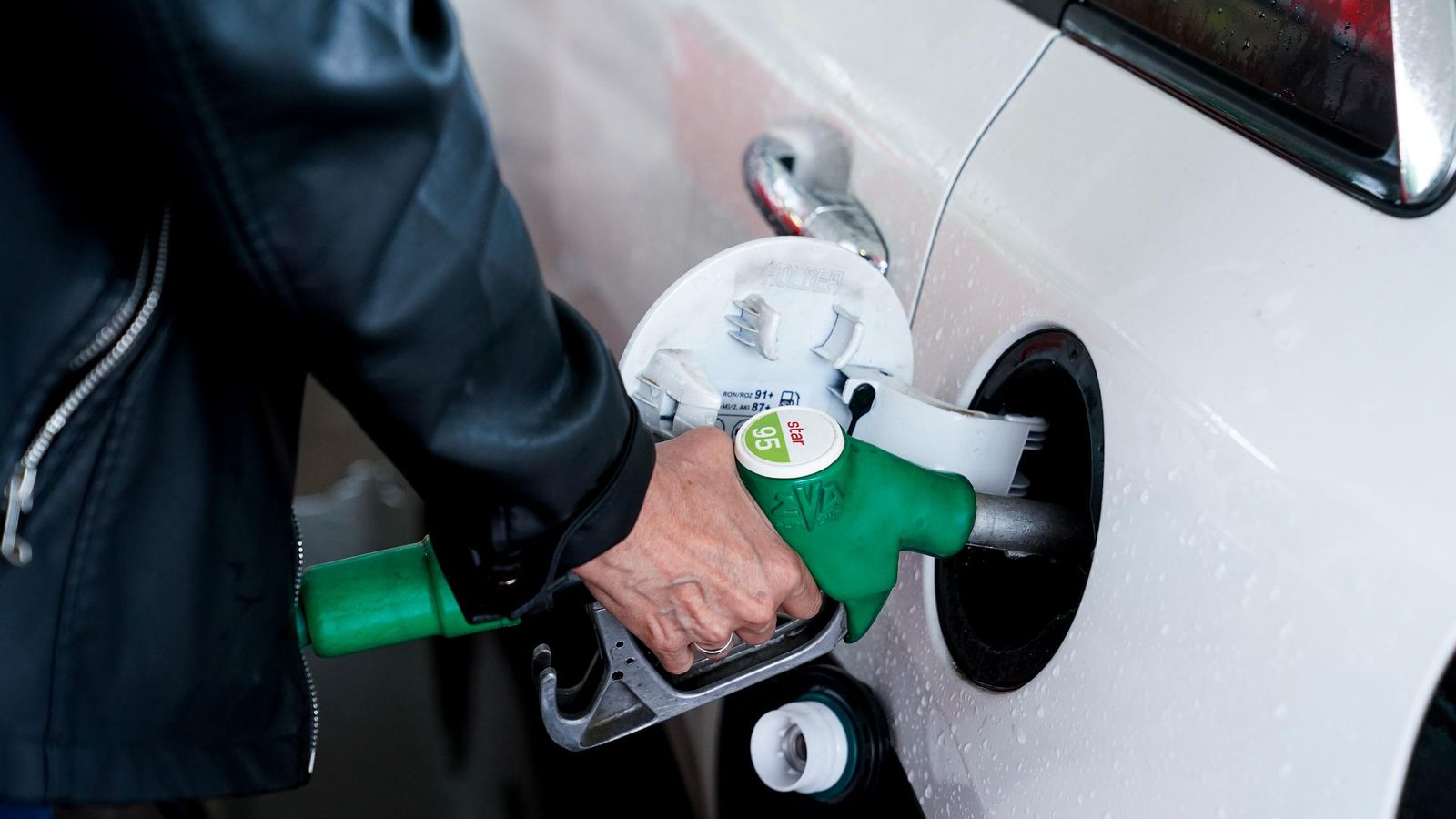 Una dona posa gasolina al seu vehicle en una gasolinera Una dona posa gasolina al seu vehicle en una gasolinera