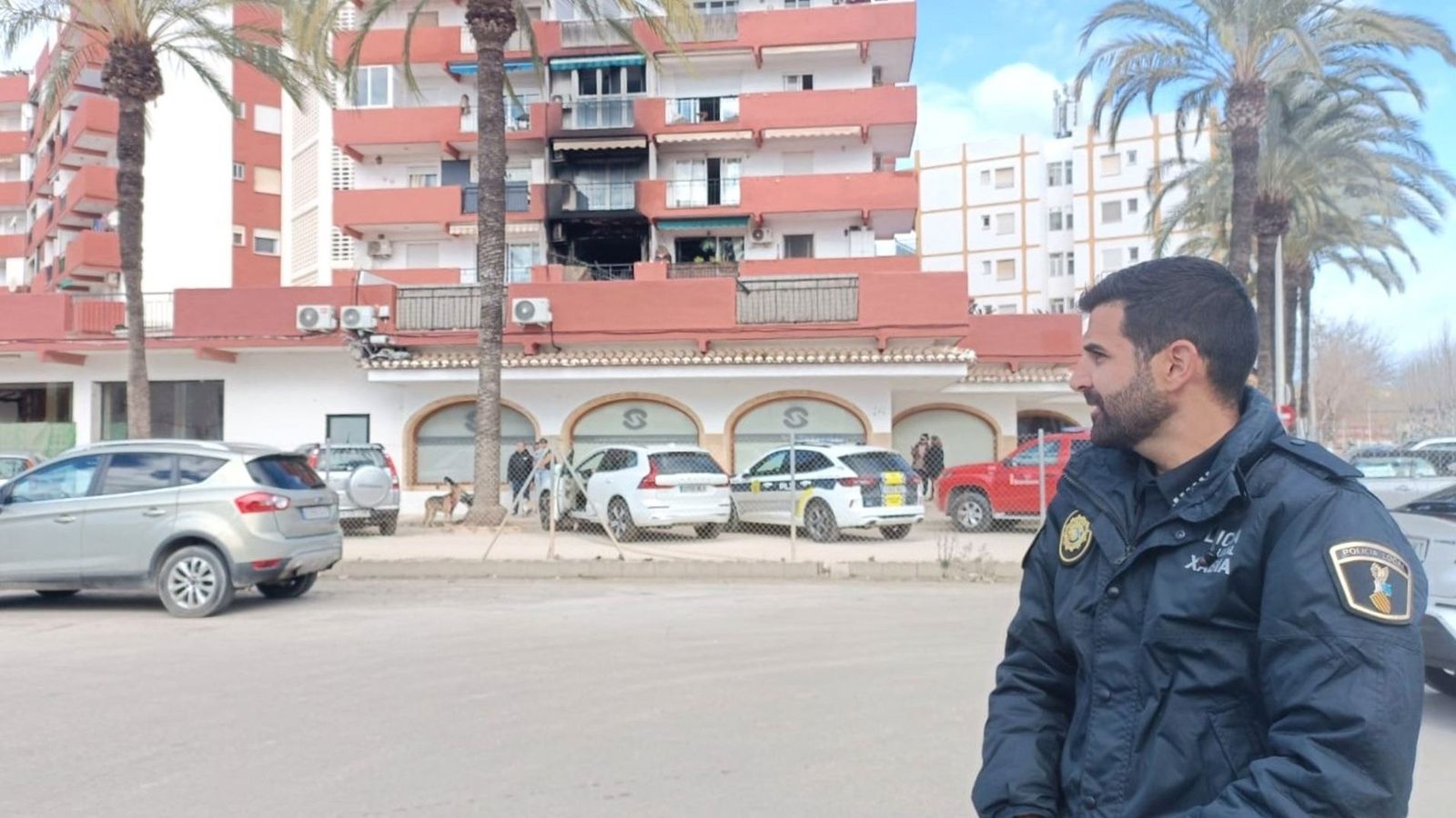 L'agent 64 de la Policia Local de Xàbia al costat de l'edifici de l'habitatge incendiat