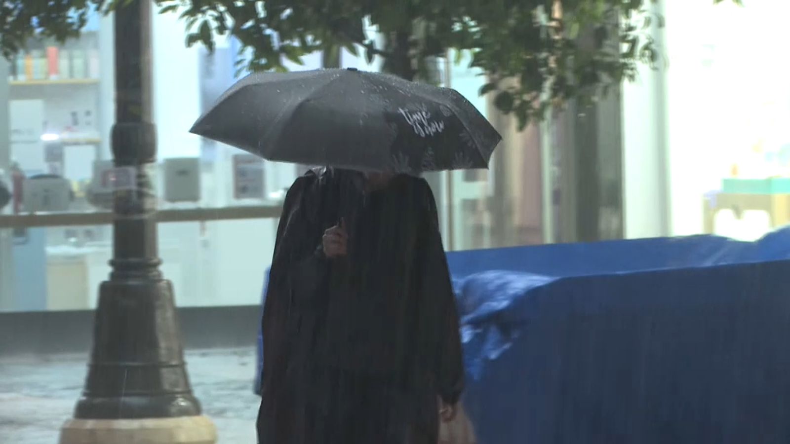 Una persona es protegix de la pluja amb un paraigua a València