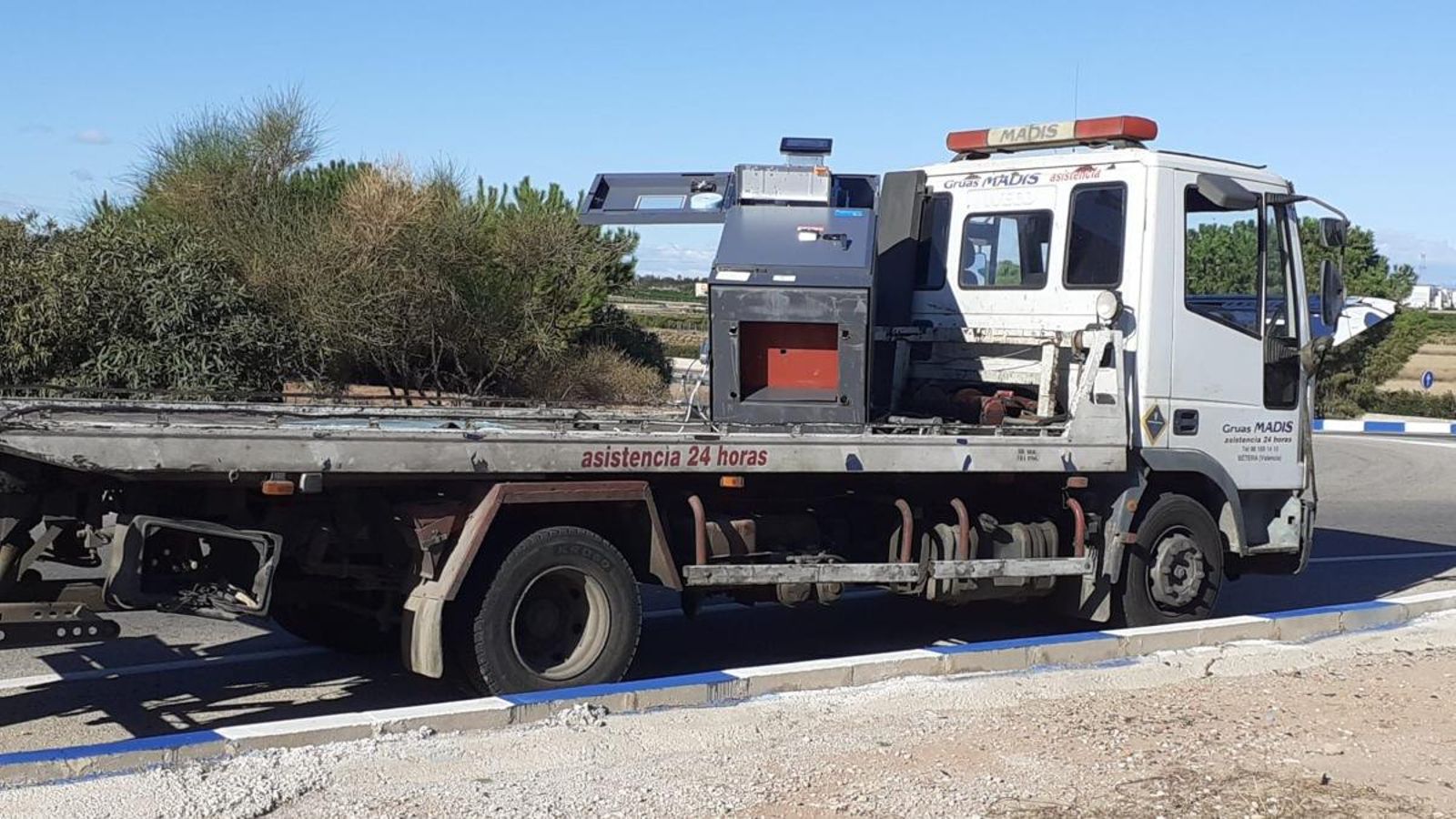 La grua amb el caixer automàtic rebentat, abandonats a la rotonda de Montcada