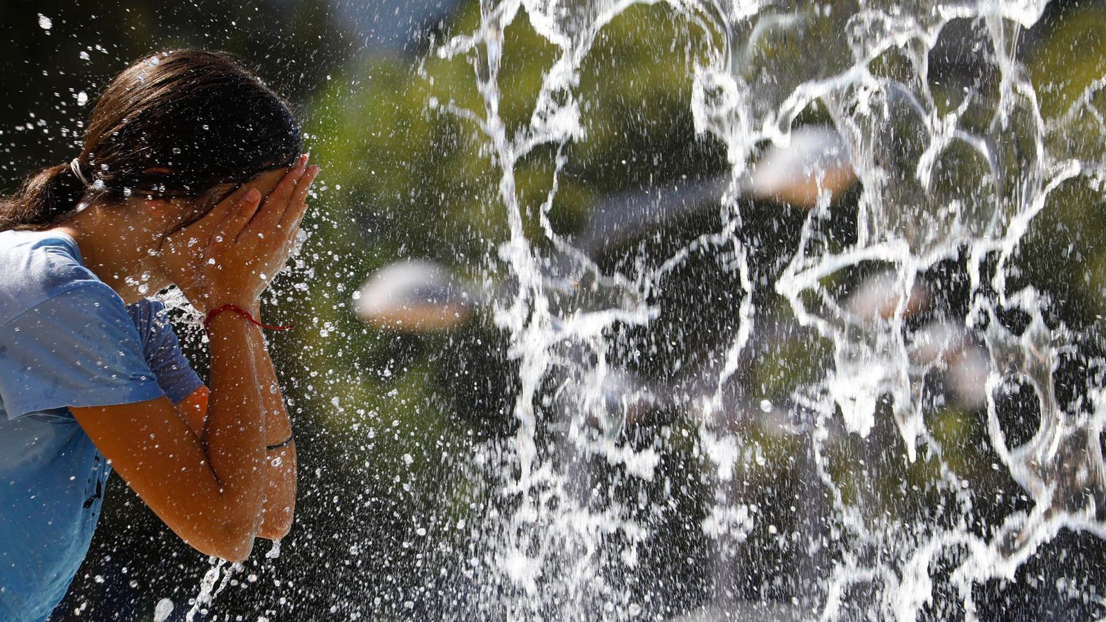 Una jove es refresca en una font