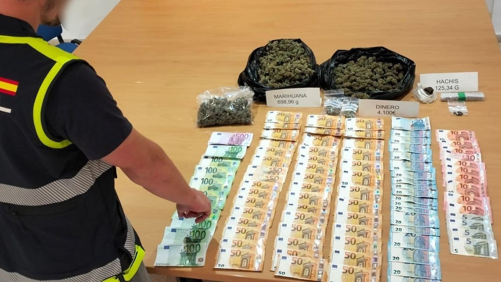 Un agent de la Policia Nacional assenyala el material incautat en el registre de la viveda de Torrent des d'on se venien les substàncies estupefaents