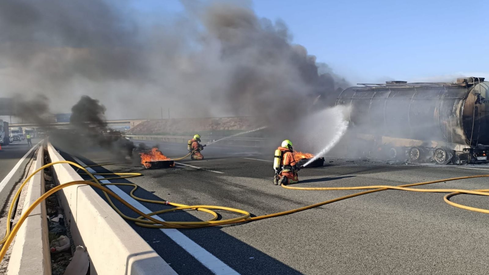 Efectius de bombers treballen en l'extinció de les flames al camió incendiant