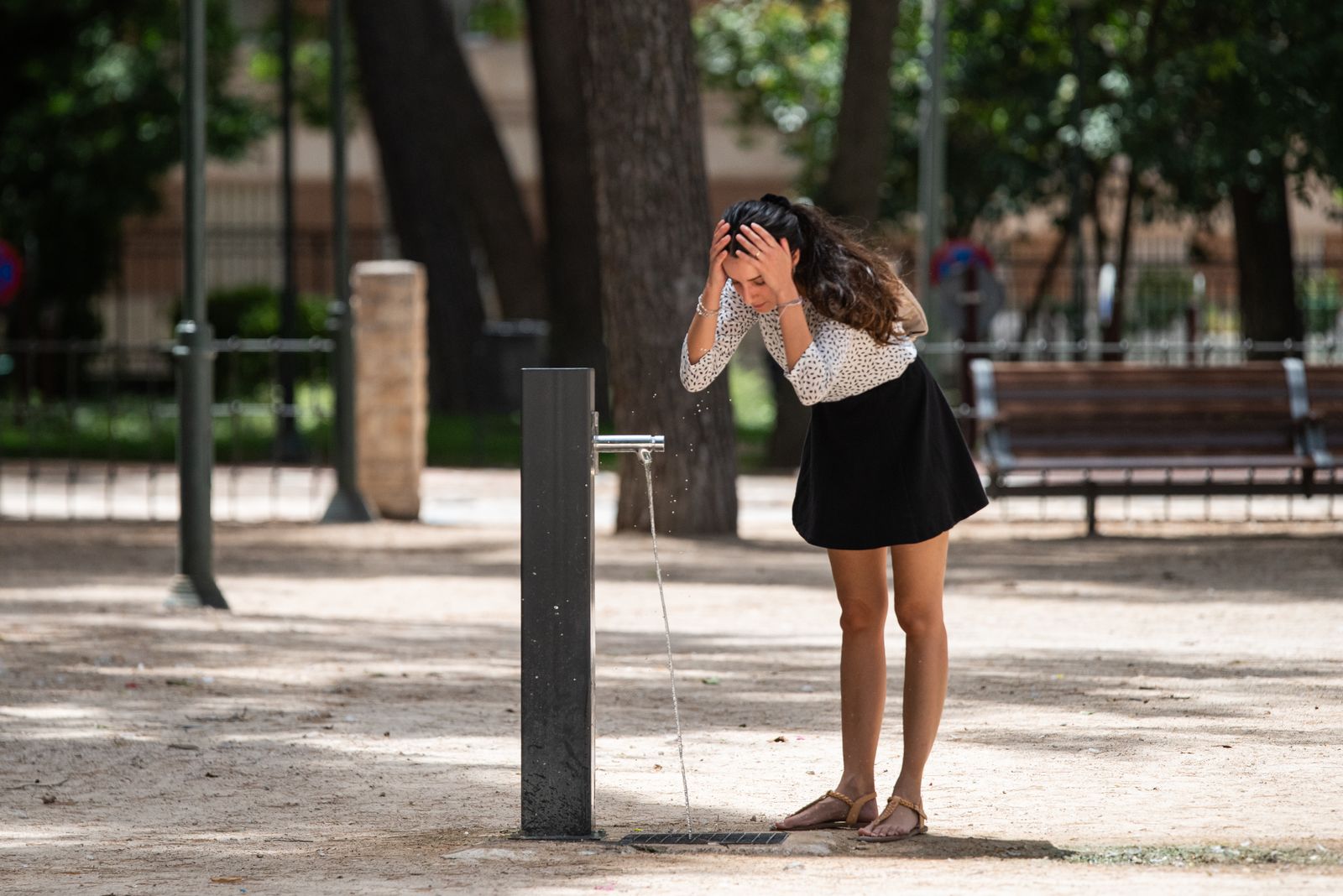 Una jove es refresca a una font durant una onada de calor