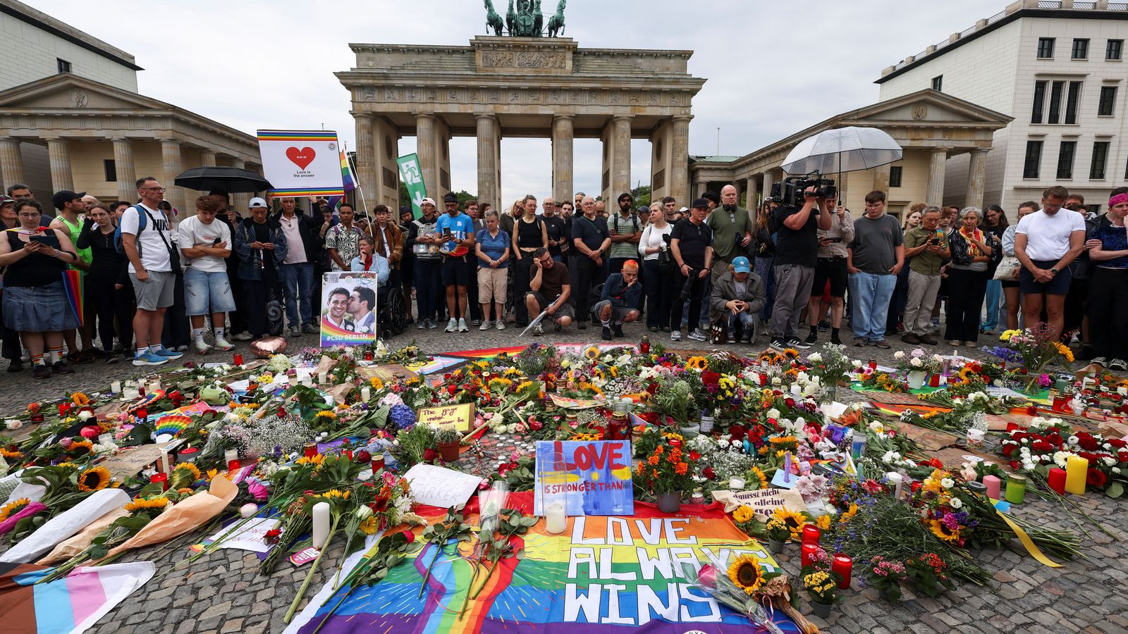 La gent es concentra al voltant de les flors, els records i les espelmes depositats a la Porta de Brandenburg després del succés mortal en què un vehicle va envestir una multitud prop de la desfilada anual del Christopher Street Day (Orgull) de Berlín, dissabte a la vesprada.