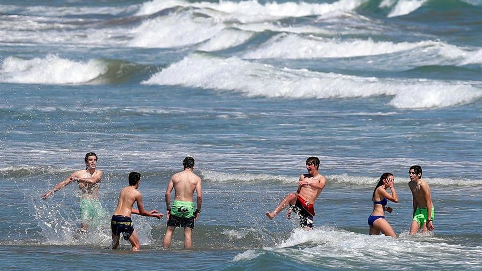 Un grup de joves pren un bany a la platja de la Malva-rosa de València