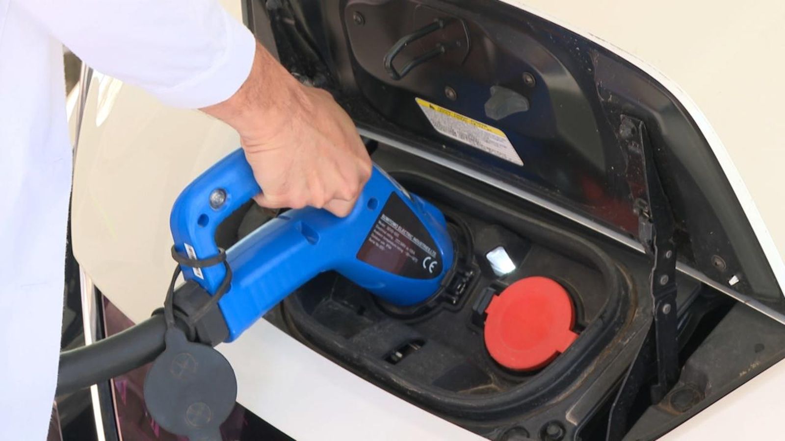 Una persona posa a carregar la bateria elèctrica d'un automòbil