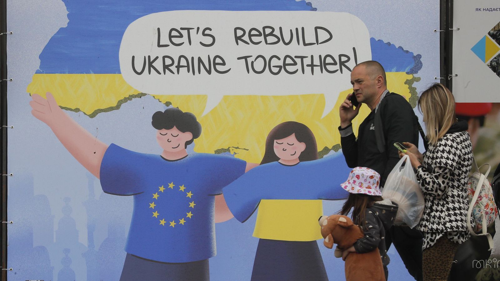 La gent camina junt a un cartell amb el lema 'Reconstruirem Ucraïna junts' en el centre de Kíiv