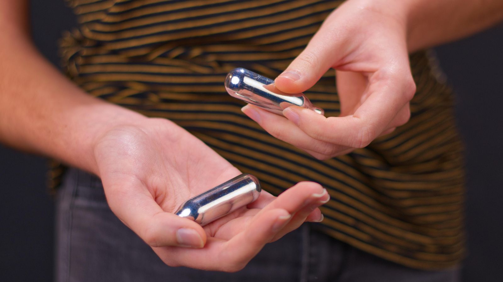 Una dona amb dos cartutxs de gas del riure a la mà