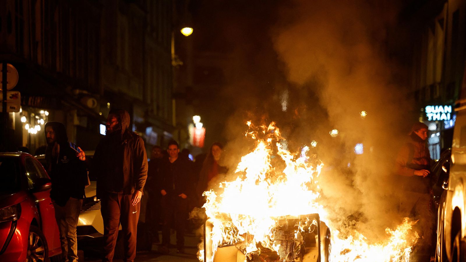 Una multitud avança al costat d'un contenidor incendiat a París