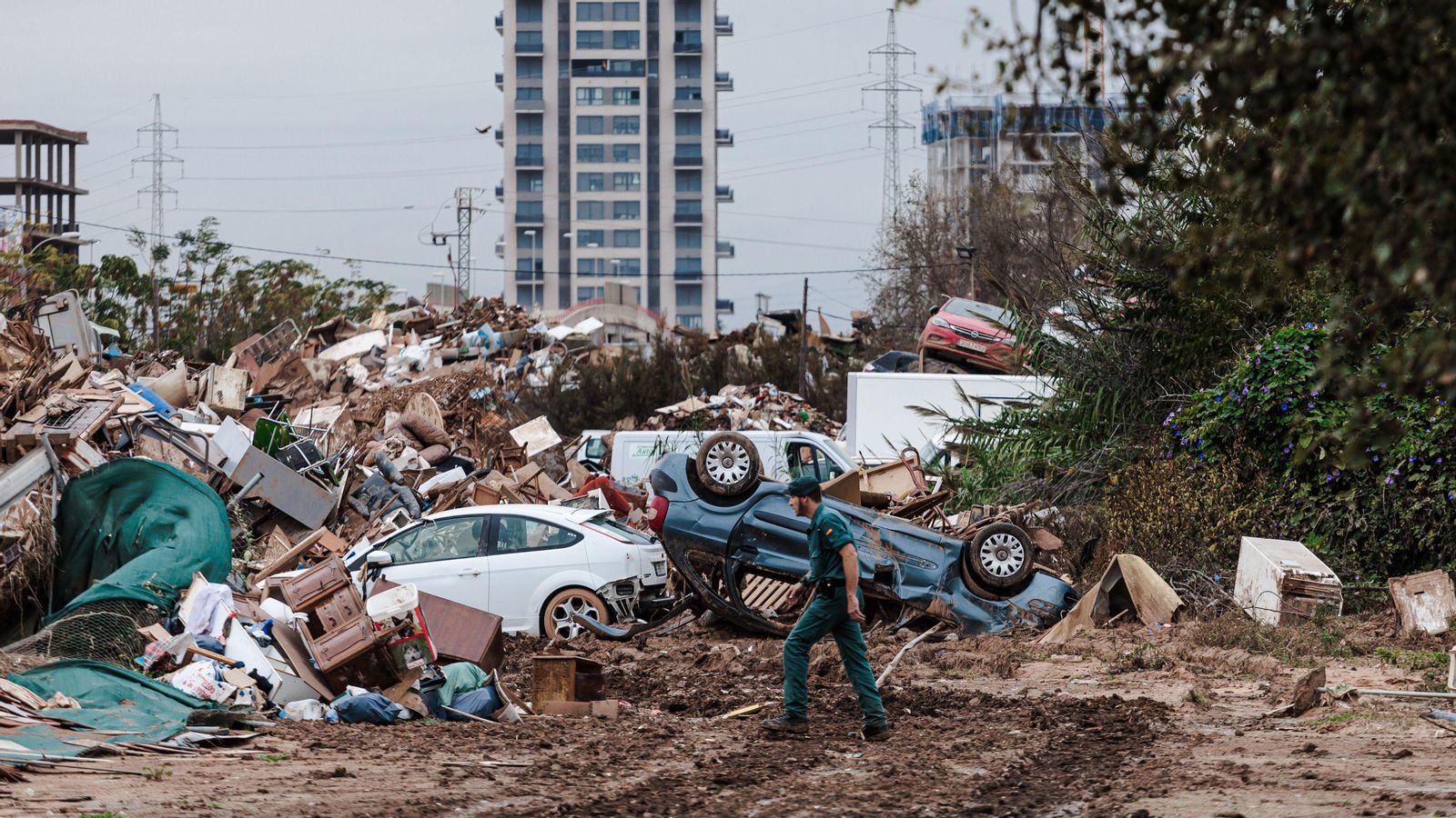Un militar avança per davant d'una muntanya de deixalles de les vivendes i vehicles que la riuada ha llançat a perdre