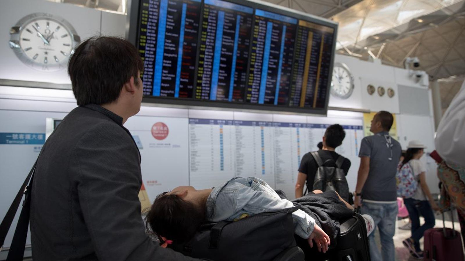 Els passatgers miren una cartellera electrònica que mostra informació de vol a l'aeroport internacional a Hong Kong