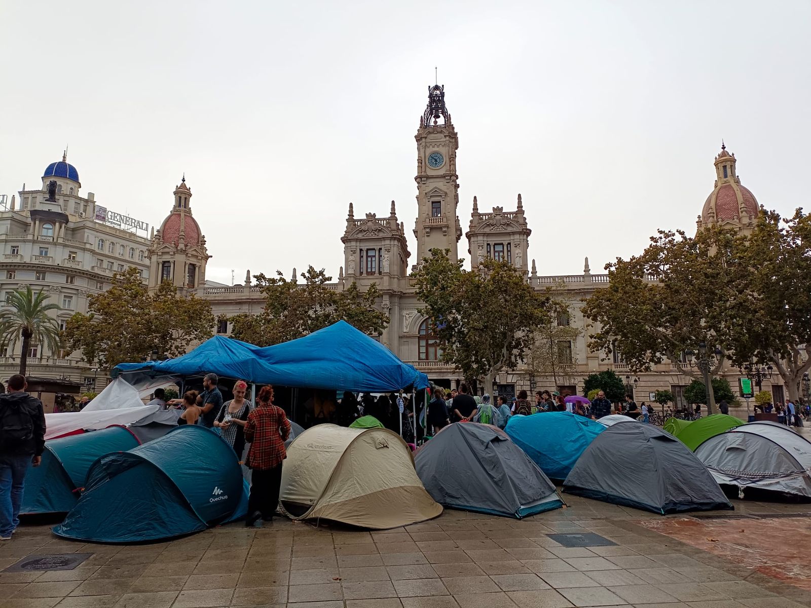 La gent es refugia de la pluja sota els tendals i manté l'acampada