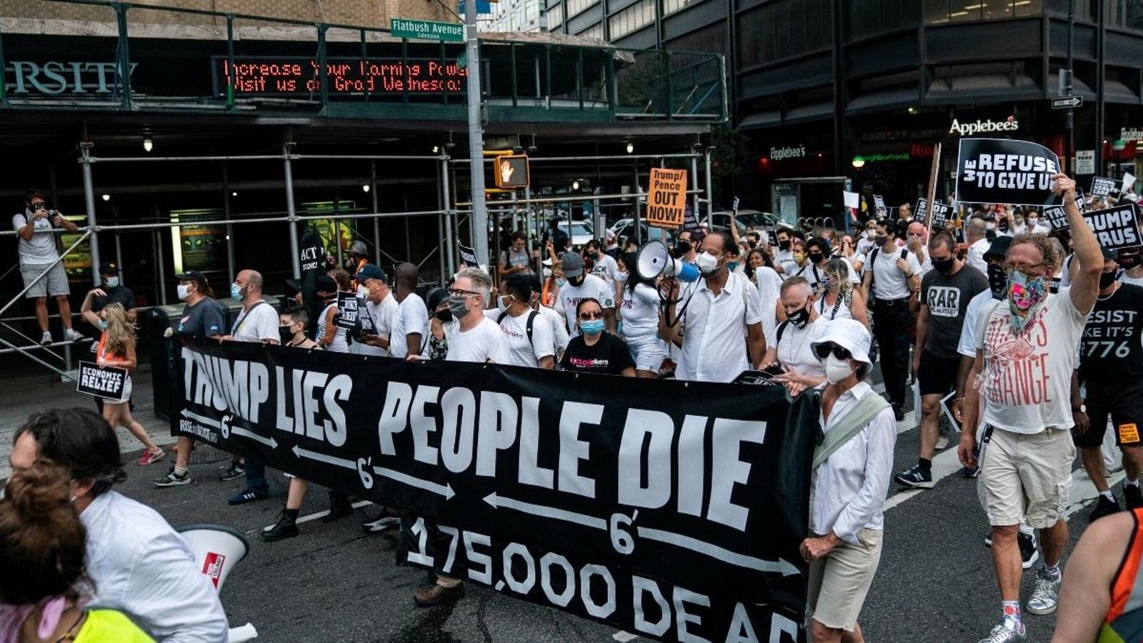 Manifestants darrere d’una pancarta que diu “Trump menteix, la gent es mor”