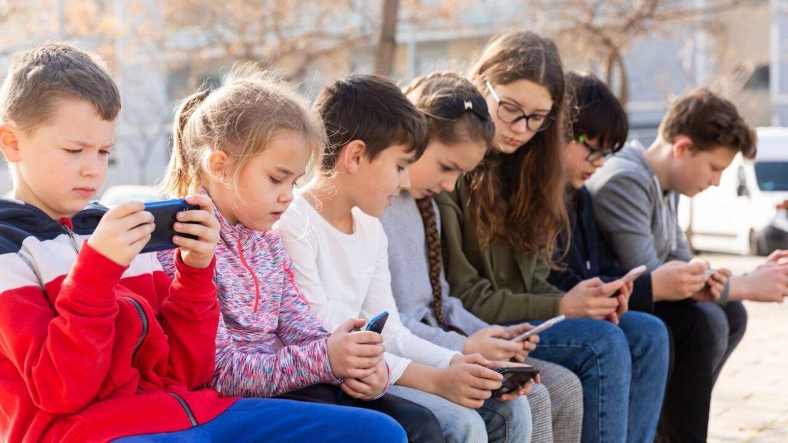 Un grup de xiquets al carrer miren telèfons mòbils