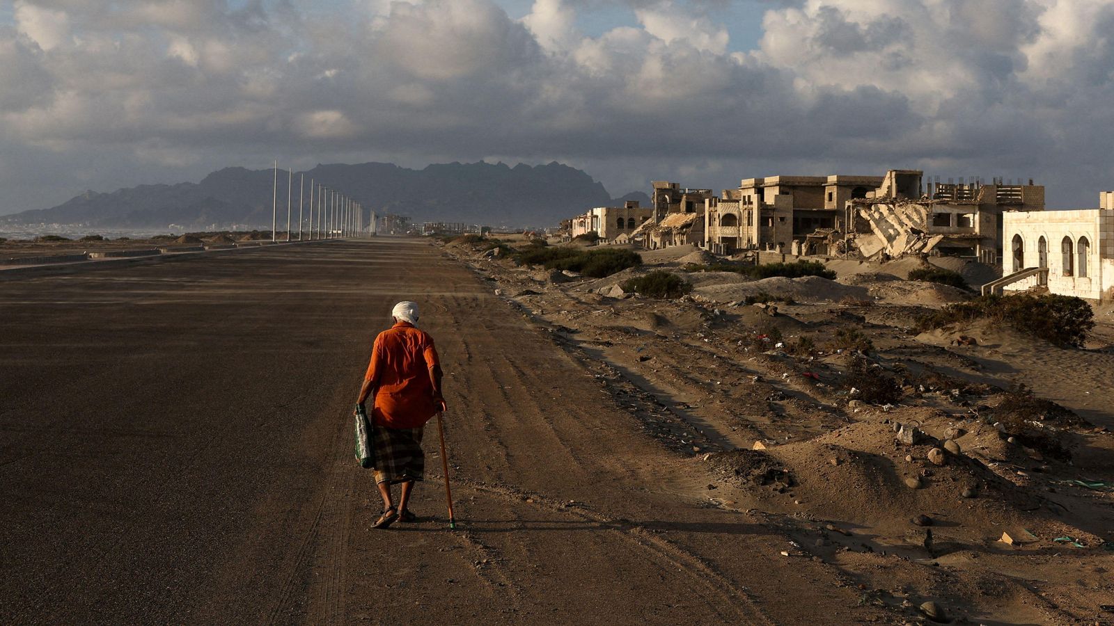Un home camina per una carretera amb edificis destruïts durant la guerra civil, a Aden (Iemen), en una imatge d'arxiu