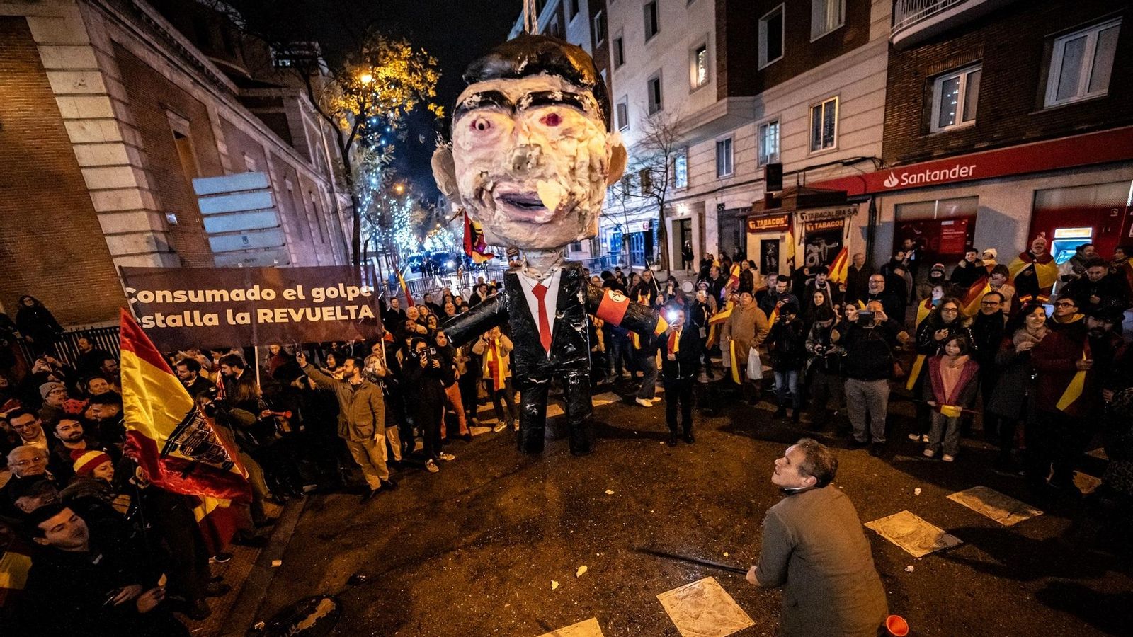 Un home colpeja amb pal un ninot del president del govern espanyol Pedro Sánchez davant de la seu del PSOE