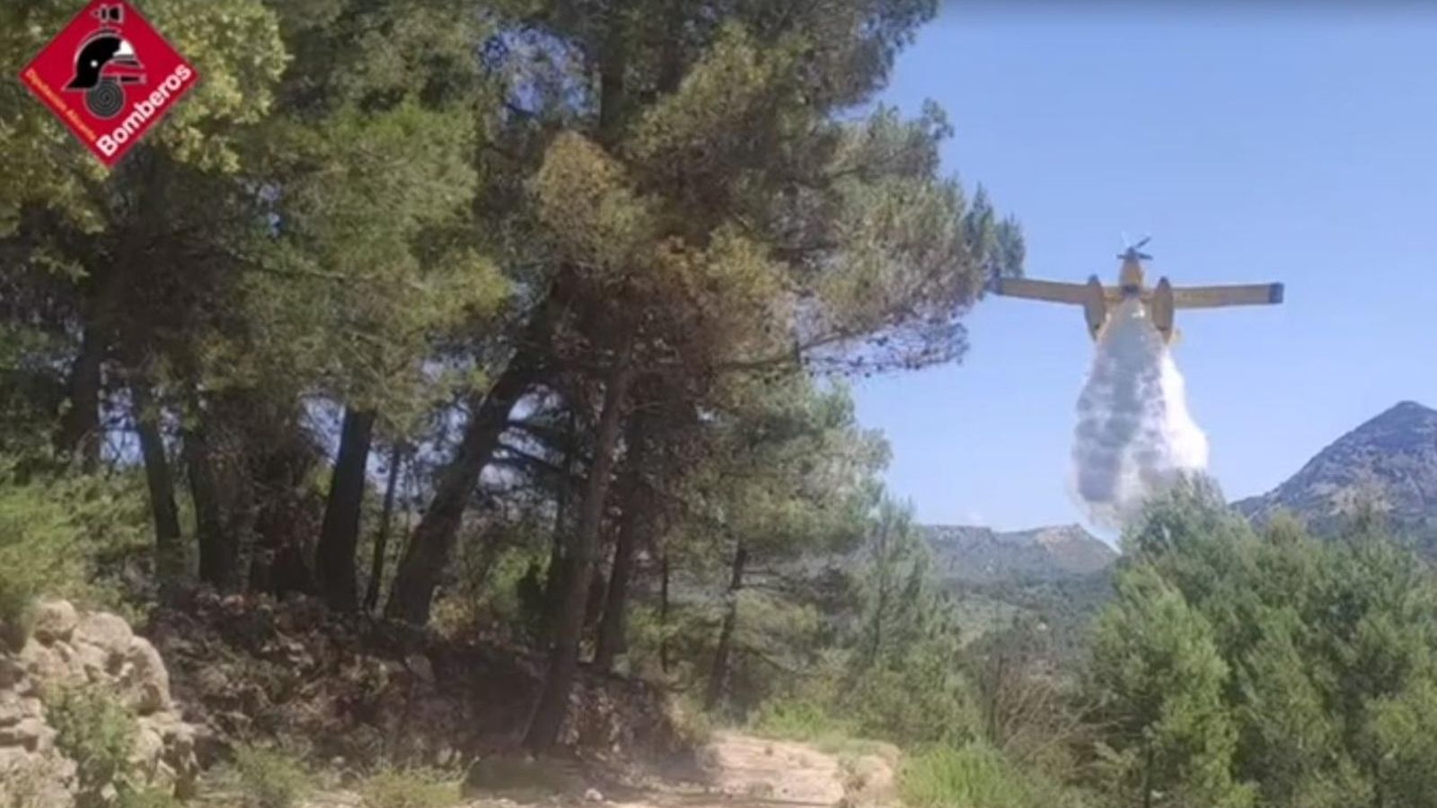 Una avioneta descarrega aigua per a apagar l'incendi forestal d'Alcoleja