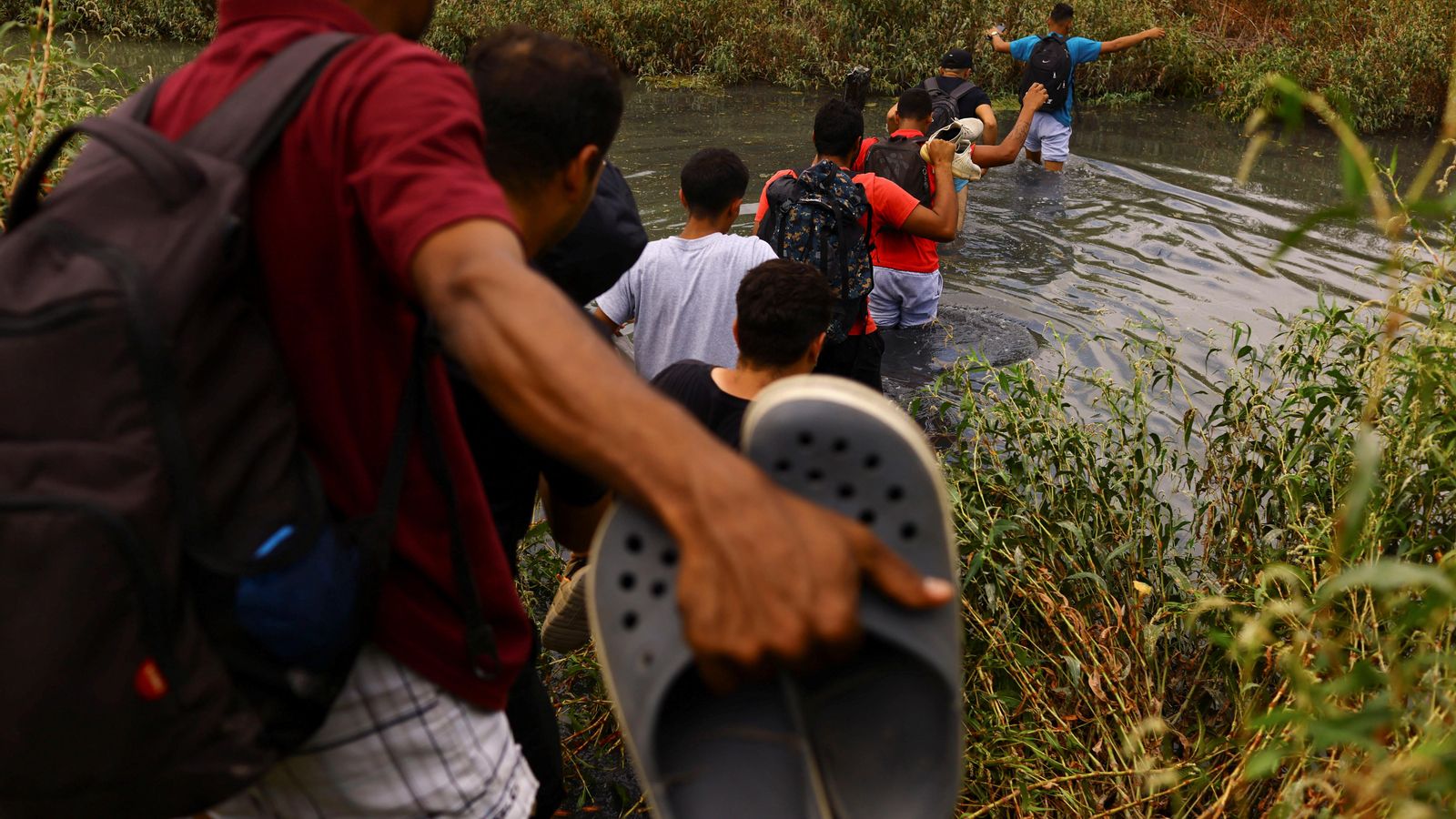 Un grup de persones migrants creua el riu que separa Mèxic dels EUA