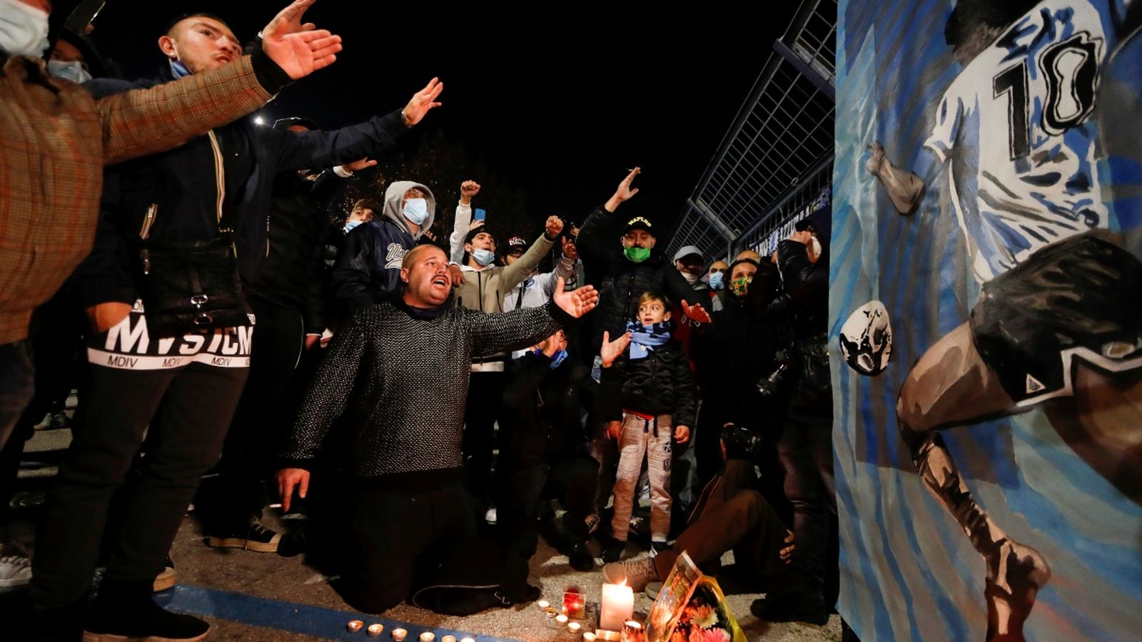 Un seguidor que porta una samarreta del club de futbol Argentinos Juniors s'agenolla davant d'un mural que representa el llegenda argentí Diego Maradona a Buenos Aires
