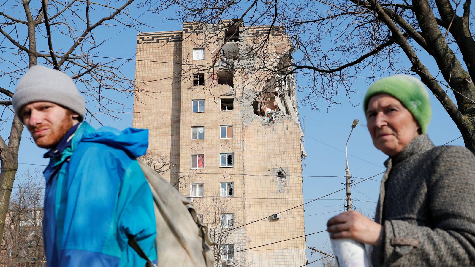 Veïns de Mariúpol caminen per davant d'un bloc d'apartaments bombardejat per les forces russes