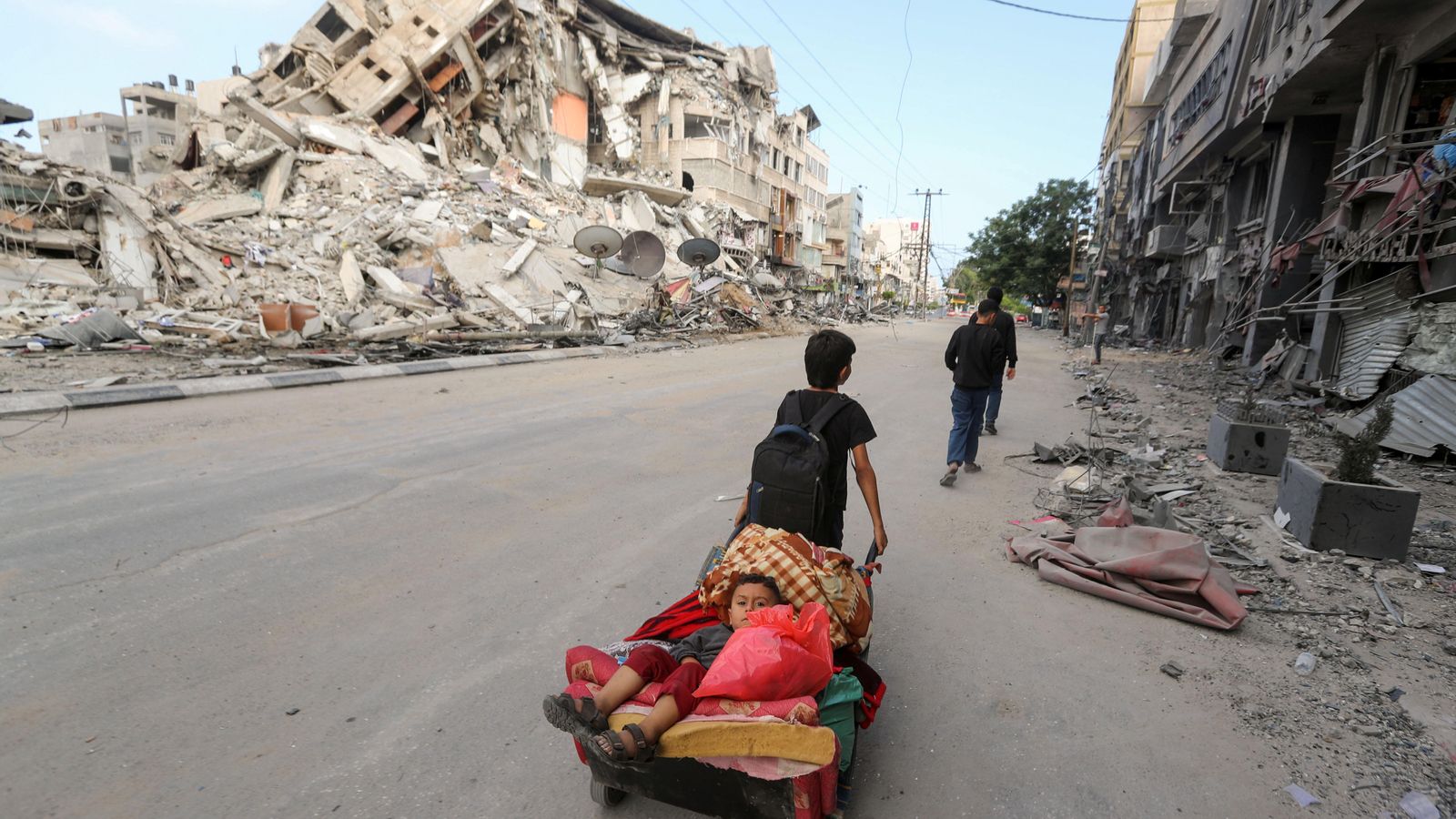 Un xiquet palestí arrossega un carro en què transporta el seu germà i les seues pertinences mentre fugen de la seua llar a Gaza