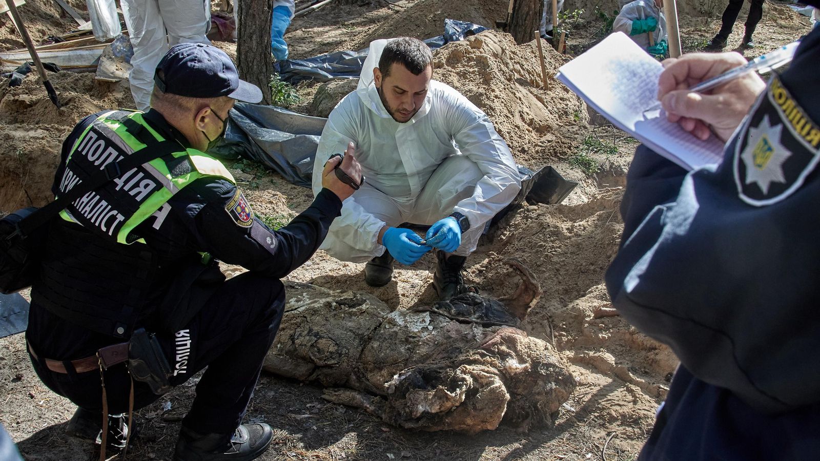 Treballadors i policies revisen els cossos desenterrats de tombes a Izyum, regió de Khàrkiv, nord-est d'Ucraïna