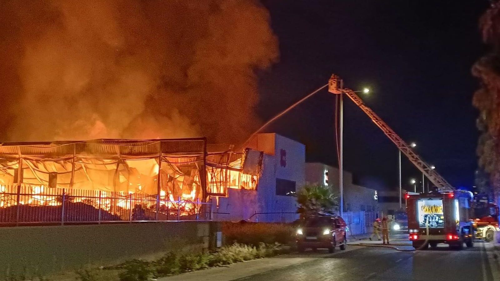 Els bombers treballen en l'extinció de l'incendi d'una nau industrial a Elda