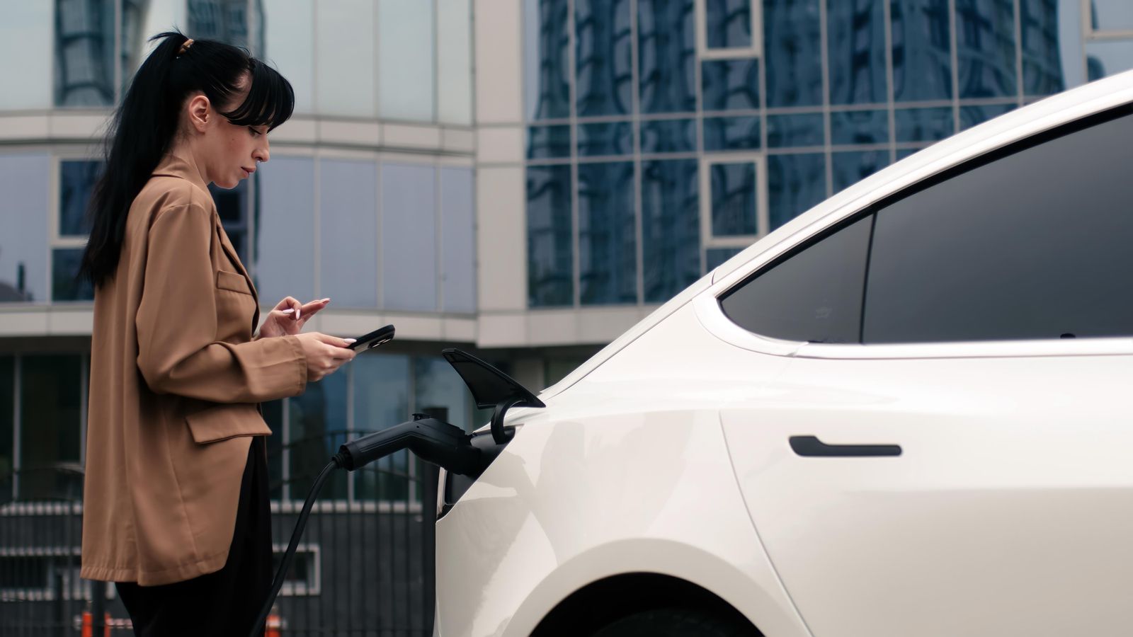Una dona carrega el seu vehicle elèctric