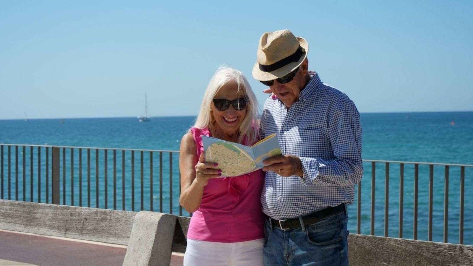 Dos persones major miren un mapa en una zona de costa, en una imatge d'arxiu Dos persones major miren un mapa en una zona de costa, en una imatge d'arxiu