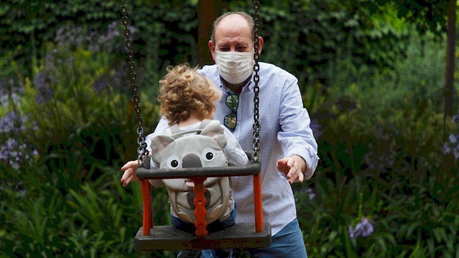 Un iaio juga amb la neta en un parc infantil