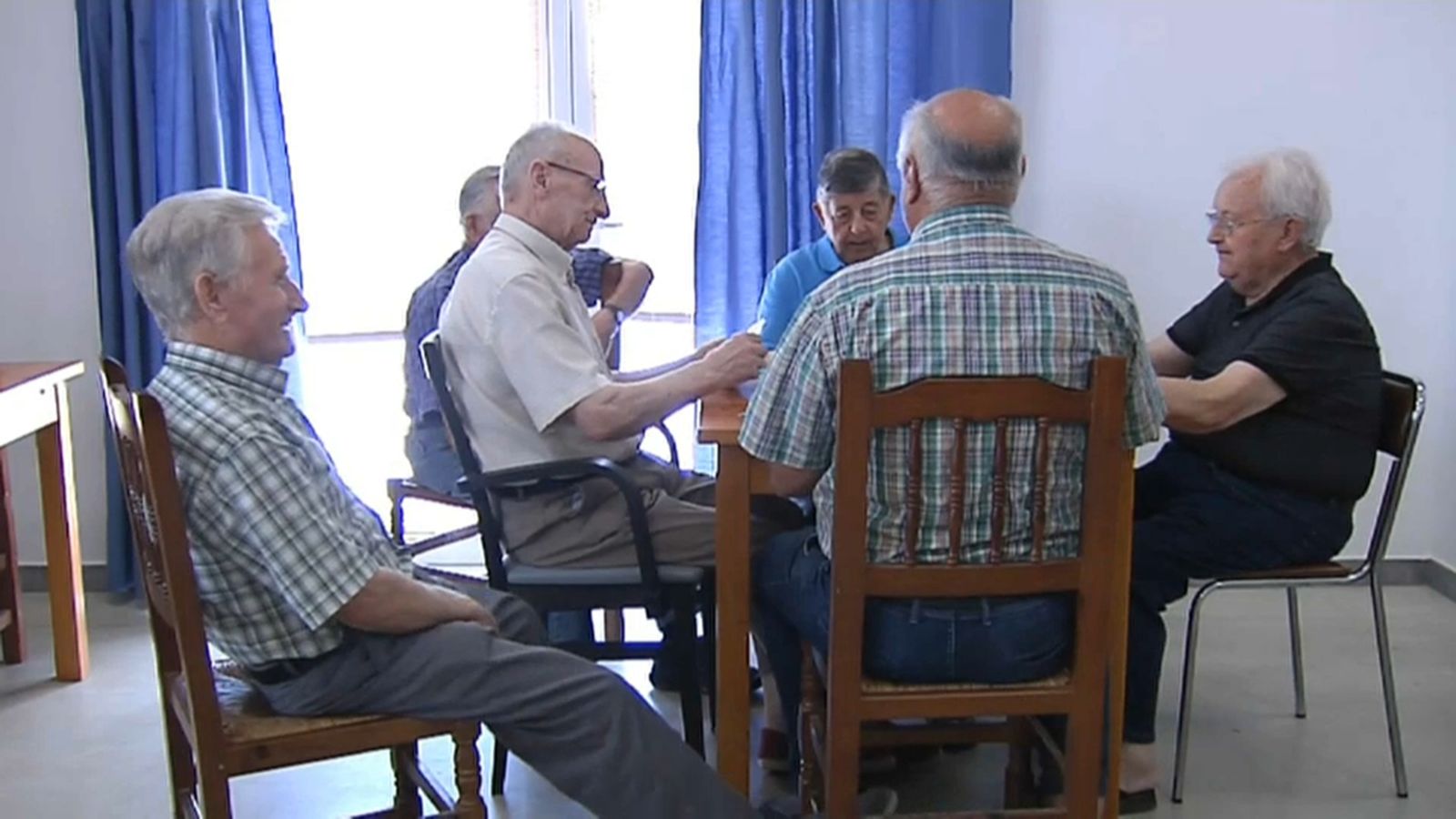 Un grup de persones majors juguen a cartes en un centre de majors