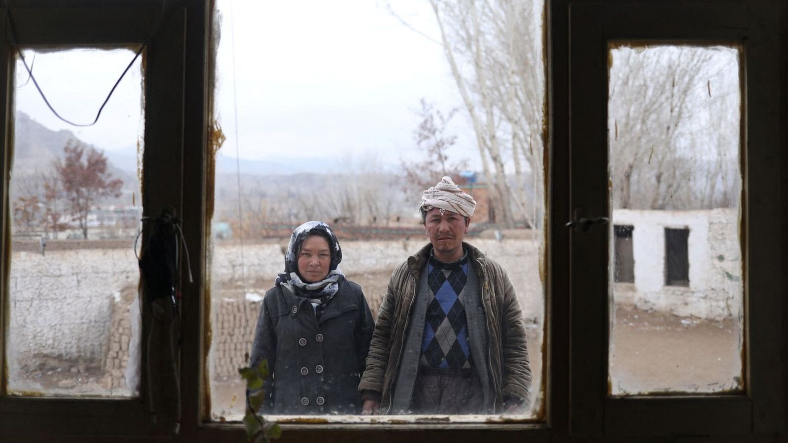 Sharifa, de 36 anys, i el seu marit, Mohammad Amin, de 45, posen a través d'una finestra a l'escola on són cuidadors a la localitat de Bamiyan, a l'Afganistan