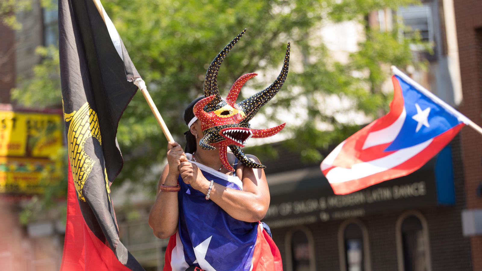 Una dona porta una màscara tradicional de Puerto Rico i banderes de l'illa i de la ciutat de Ponce Una dona porta una màscara tradicional de Puerto Rico i banderes de l'illa i de la ciutat de Ponce