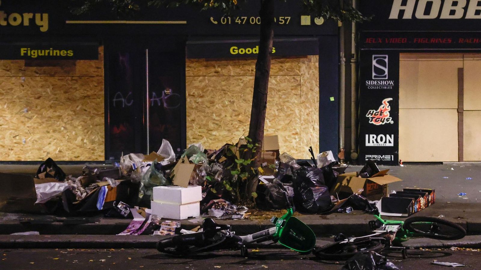 Mobiliari urbà desfet davant d'unes tendes amb els aparadors protegits arran dels actes violents que ha viscut França el cap de setmana
