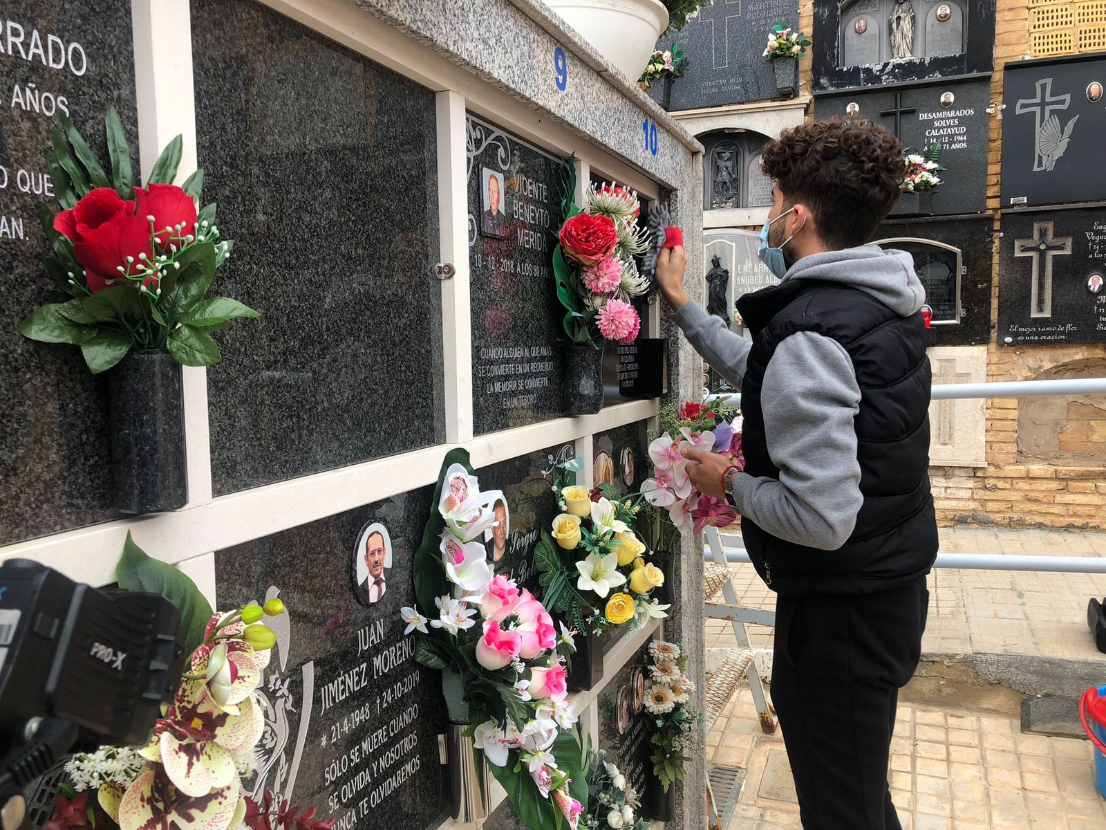 Un jove neteja la làpida d'un familiar